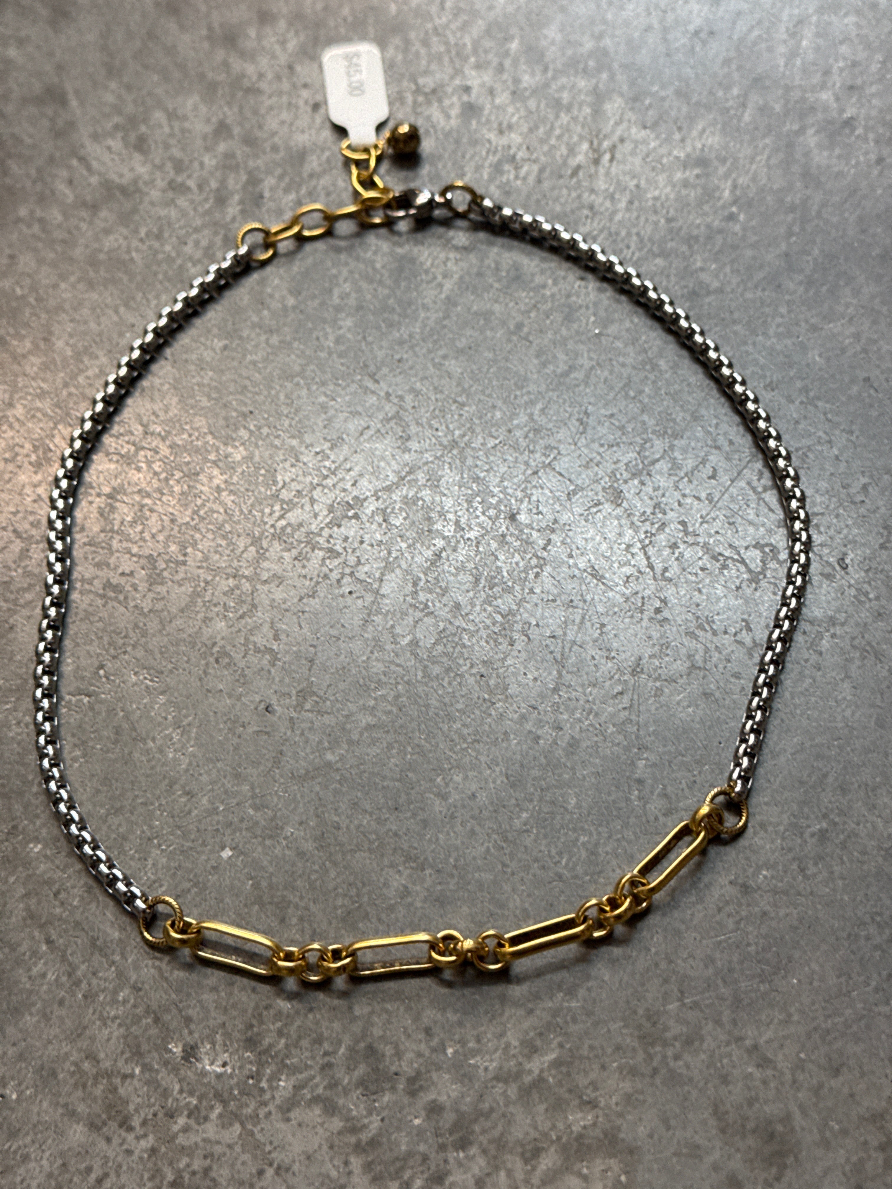 Two chain necklaces on a gray surface