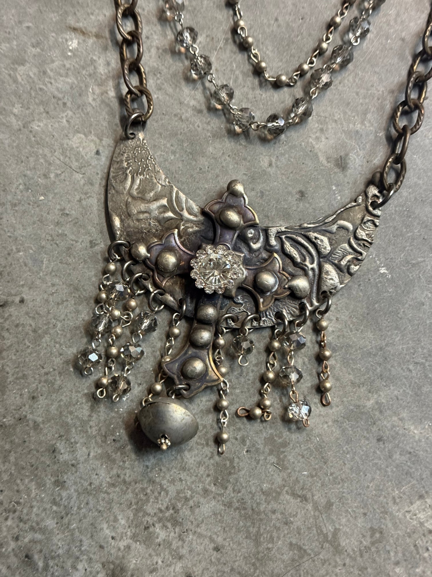 Silver necklace with floral design on a textured surface