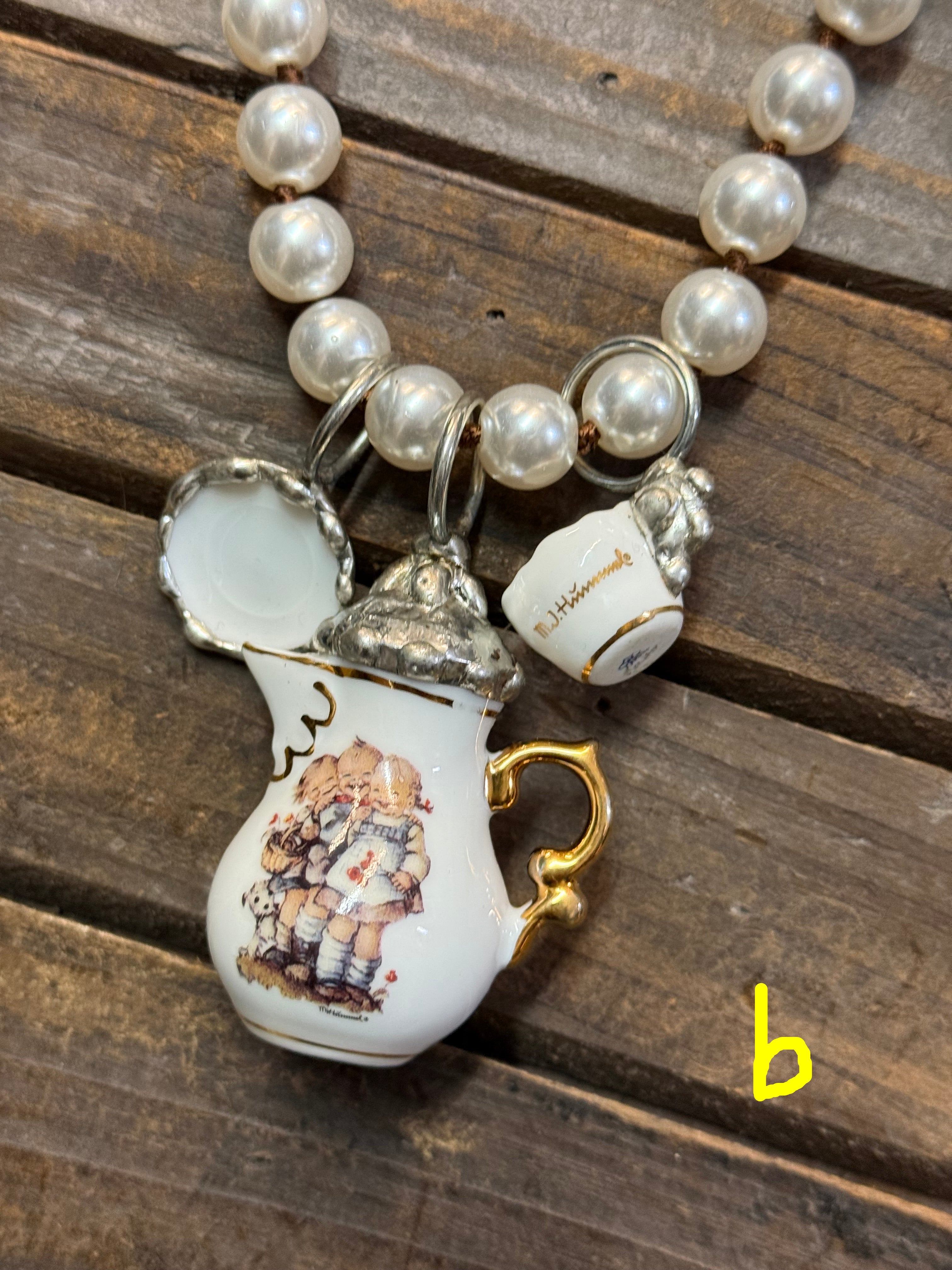 Pearl necklace with decorative teapot charms on a wooden surface