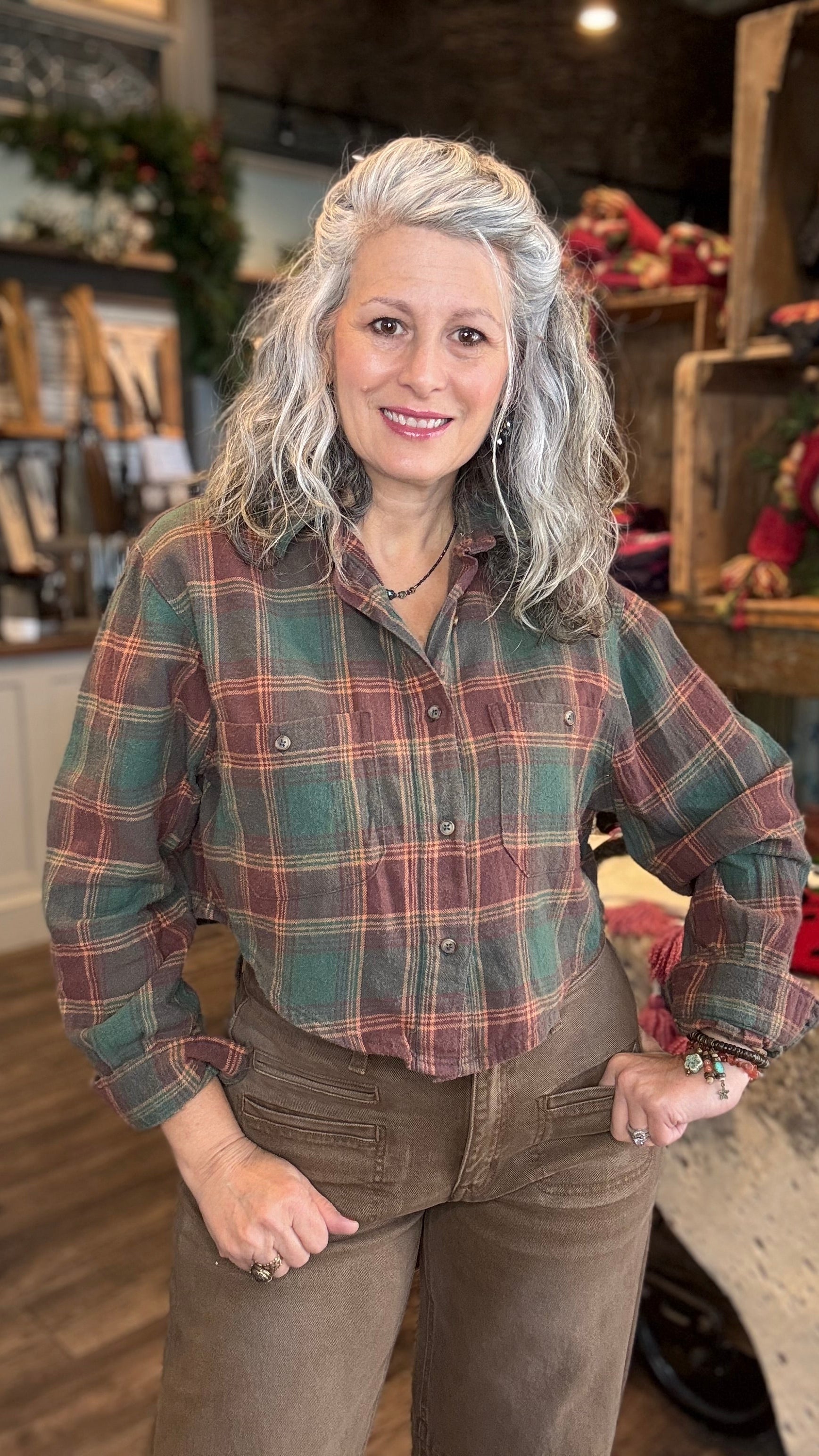 Woman wearing a green plaid crop shirt and brown pants in a store setting
