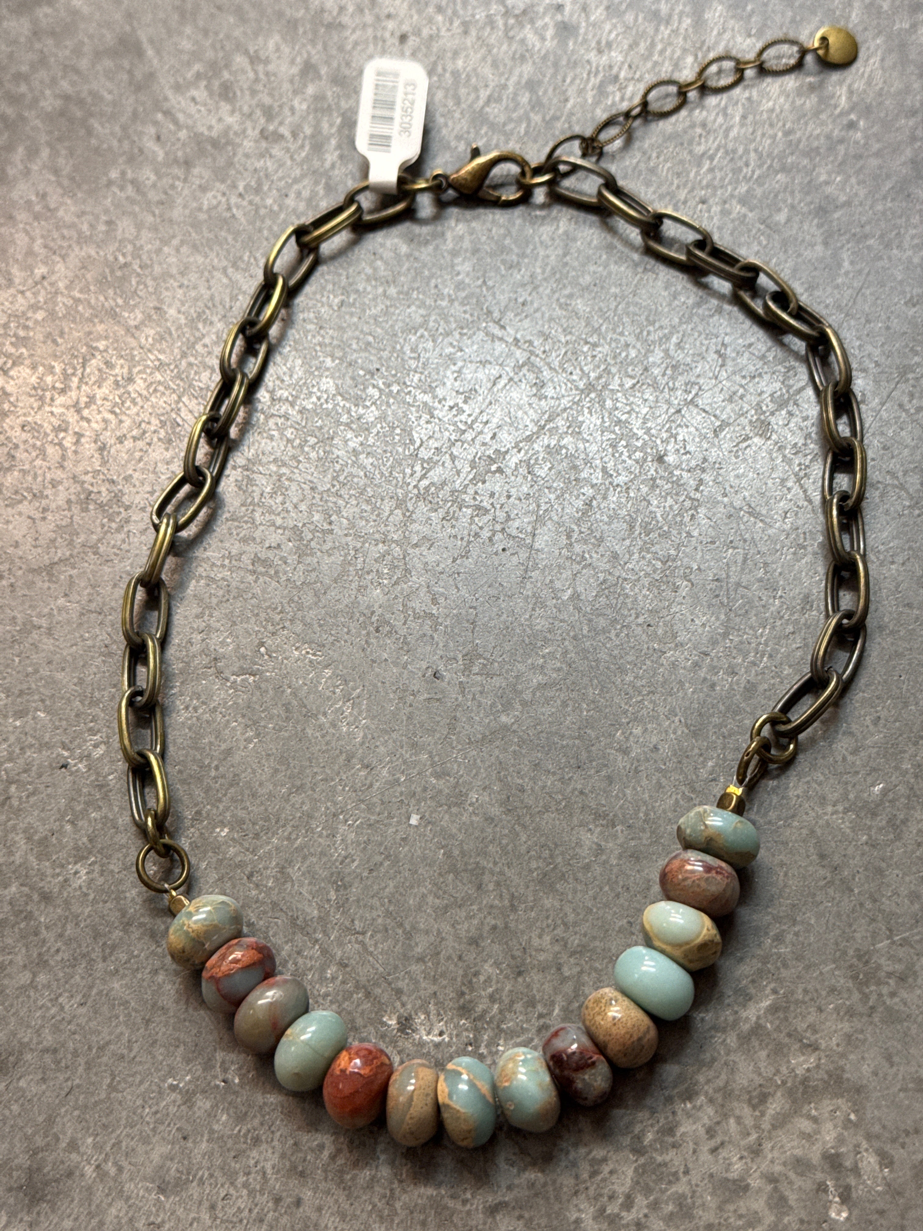 Necklace with beaded chain on a gray surface