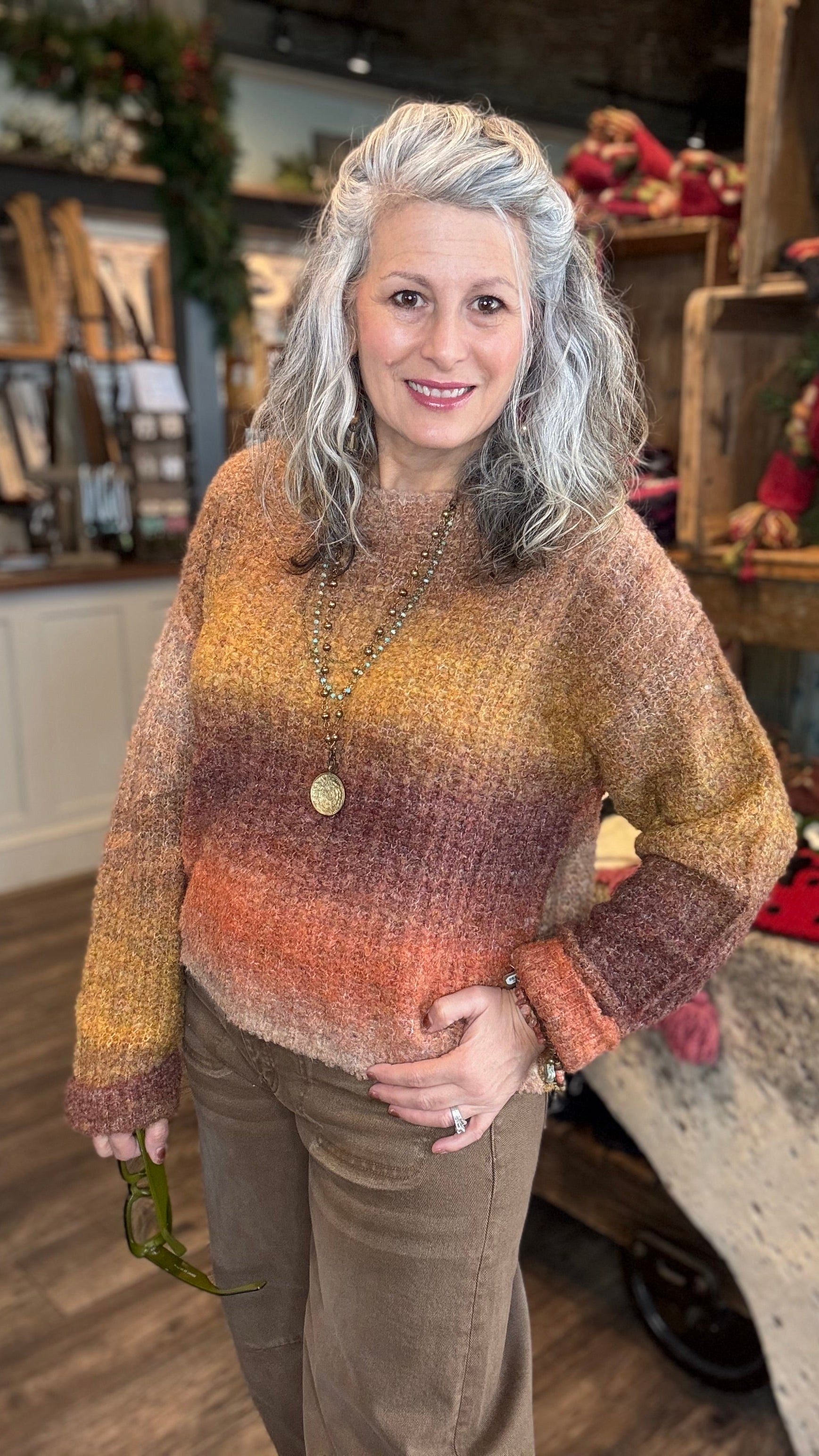 Woman wearing a colorful sweater in a store setting with various items in the background