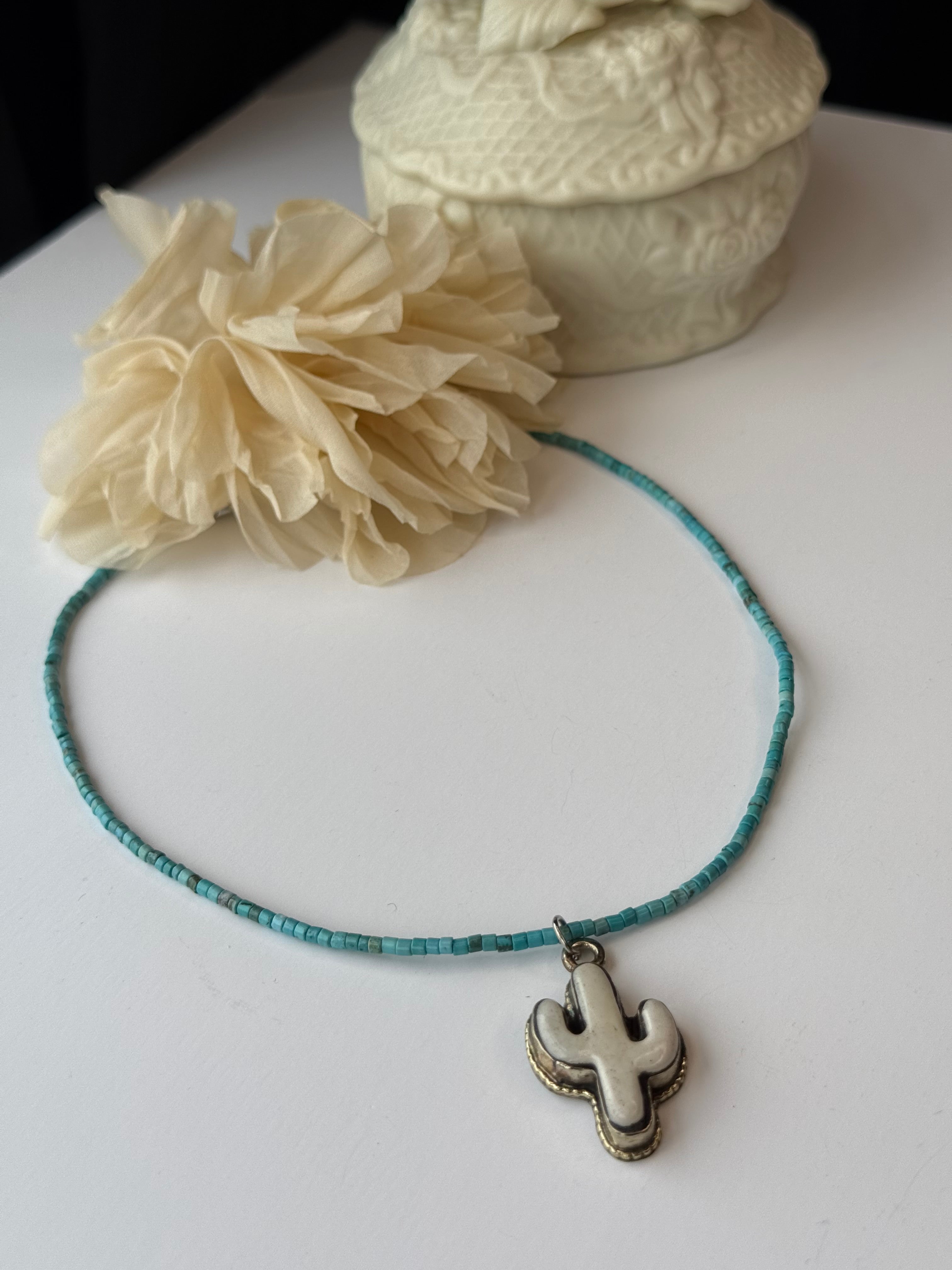 Necklace with a cactus pendant on a white surface