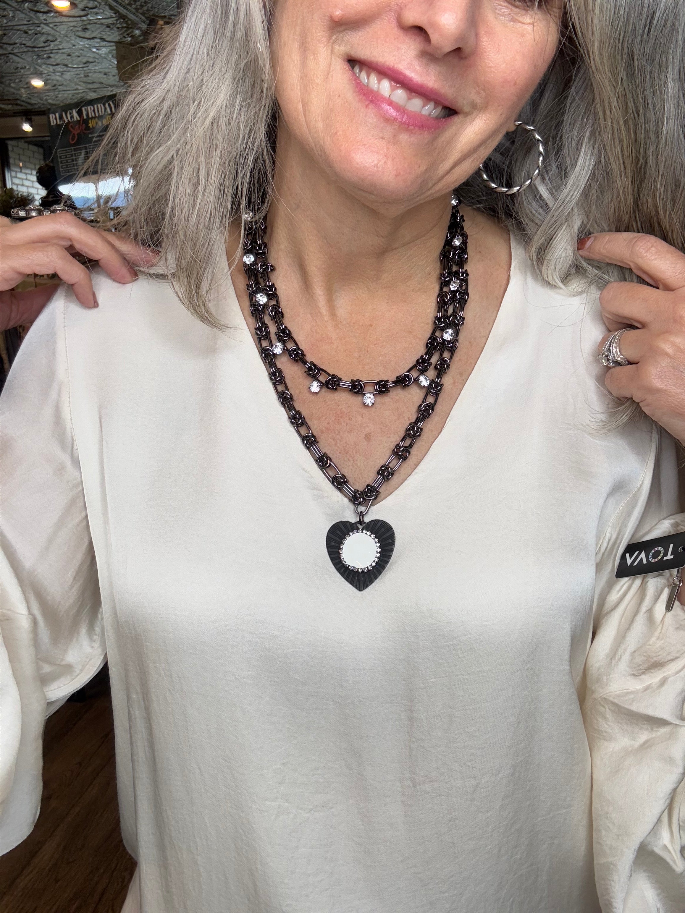 Woman wearing a white outfit with black embellishments, smiling.