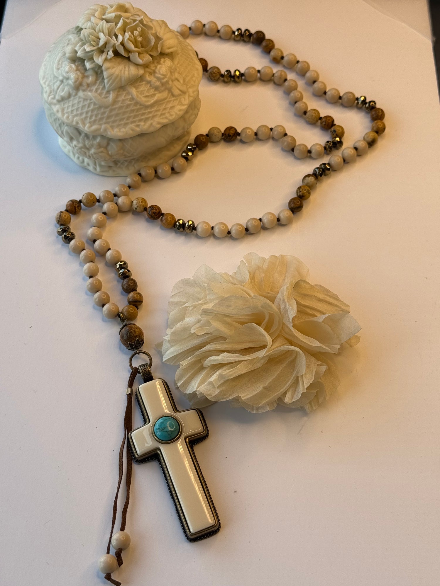 Necklace with beads and a cross pendant on a white surface