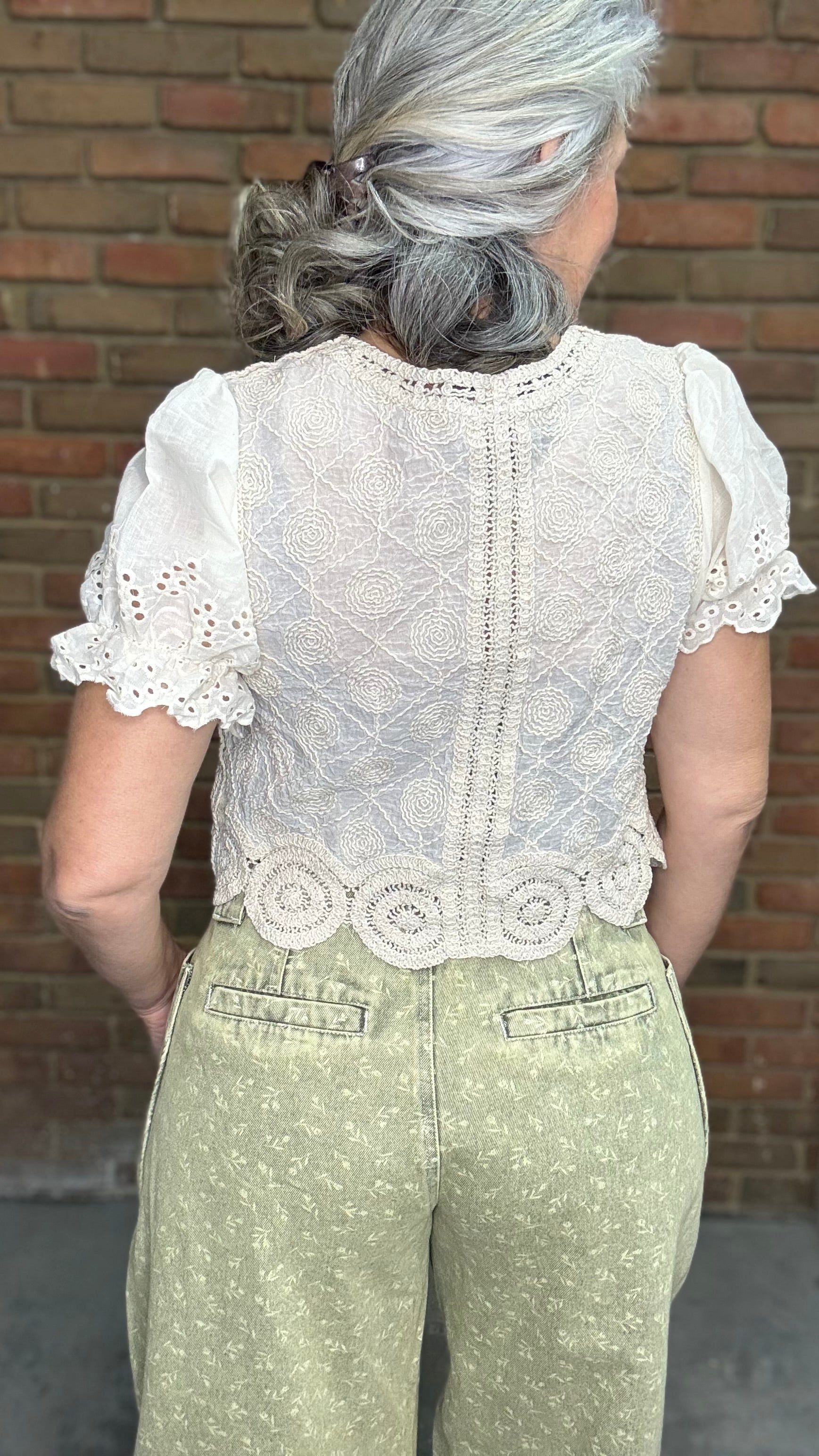 Woman wearing the Crochet Embroidery Button-Up Top and Floral Printed Barrel Pants with a brick wall background