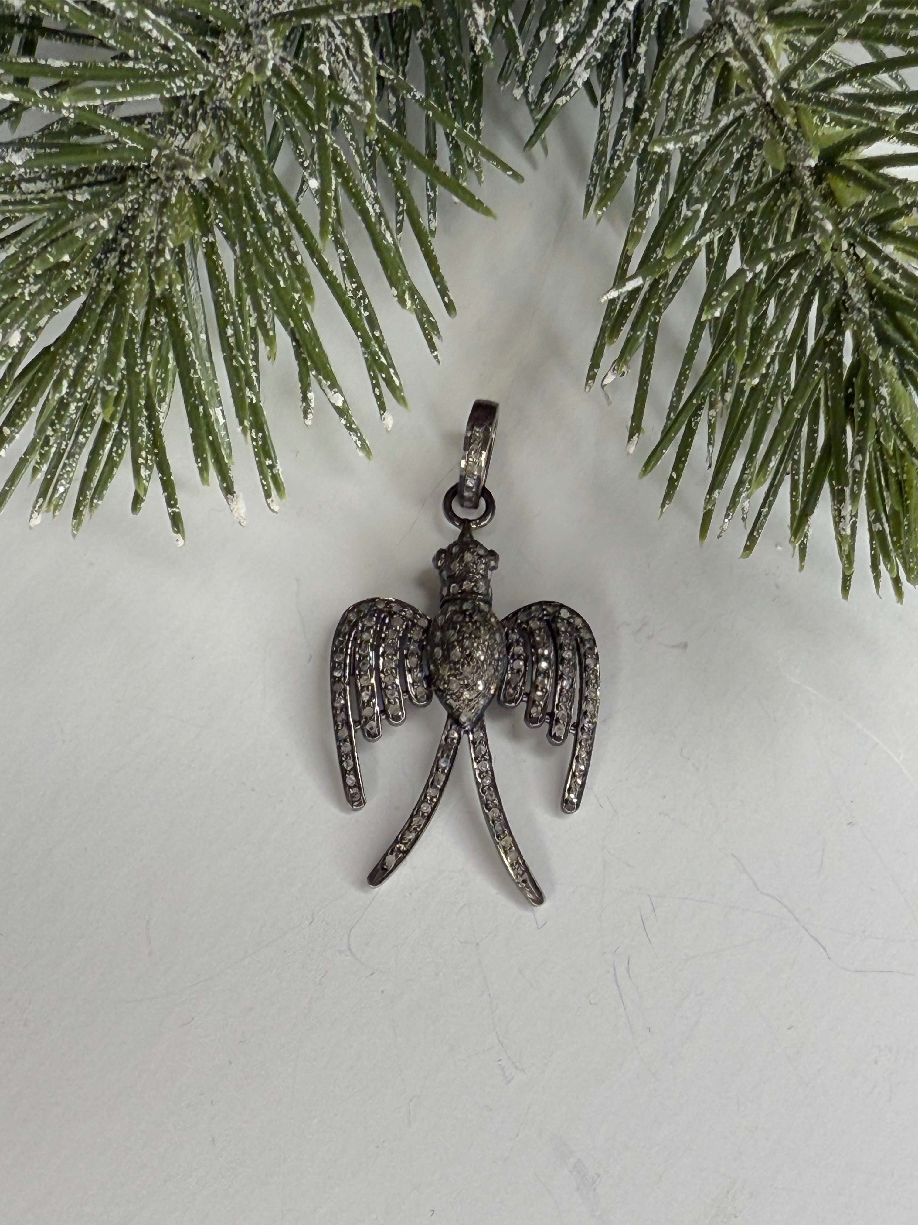 Bird shaped pave diamond pendant on a white background with greenery.