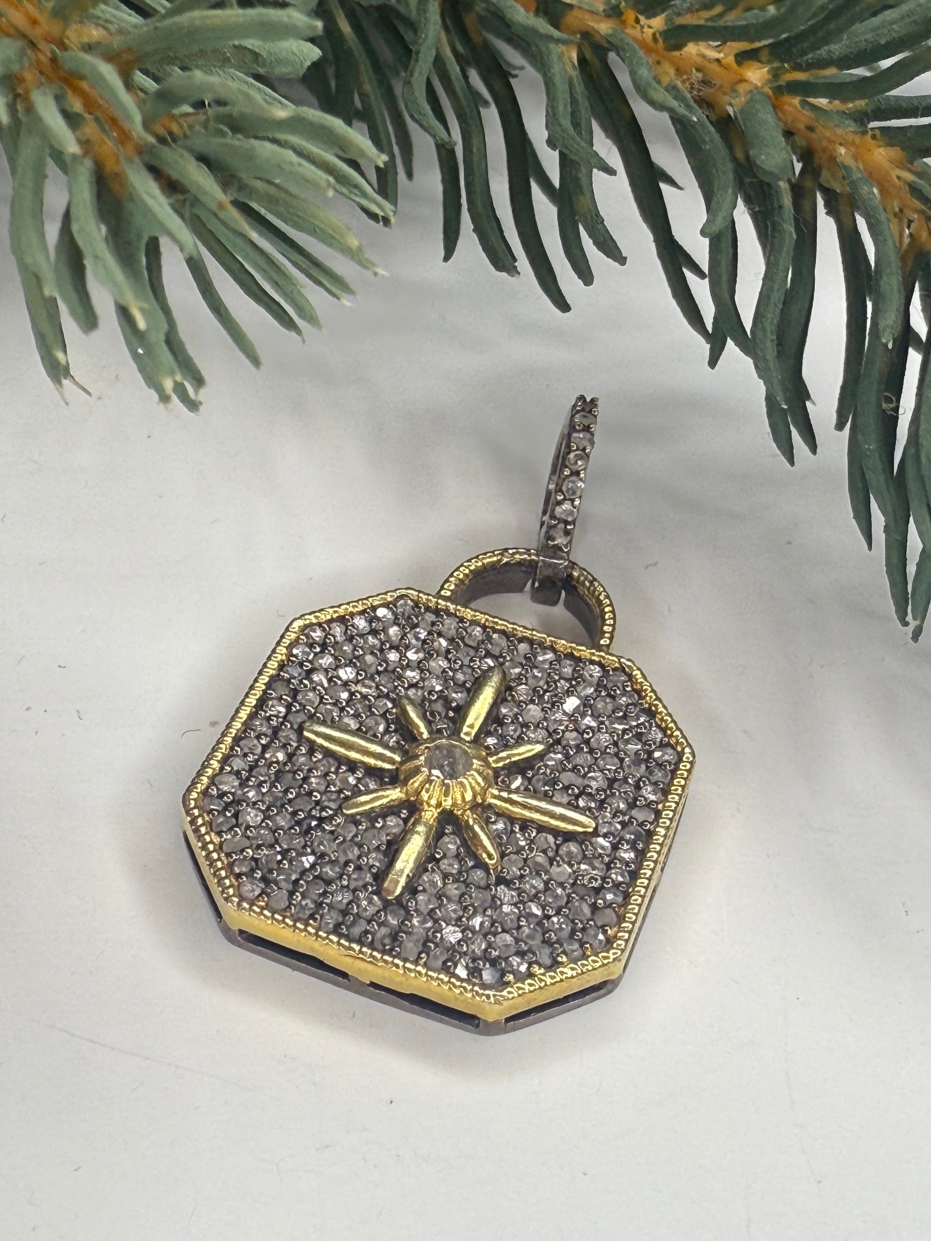 Lock shaped pendant with pave diamonds and a star design on a white surface with greenery