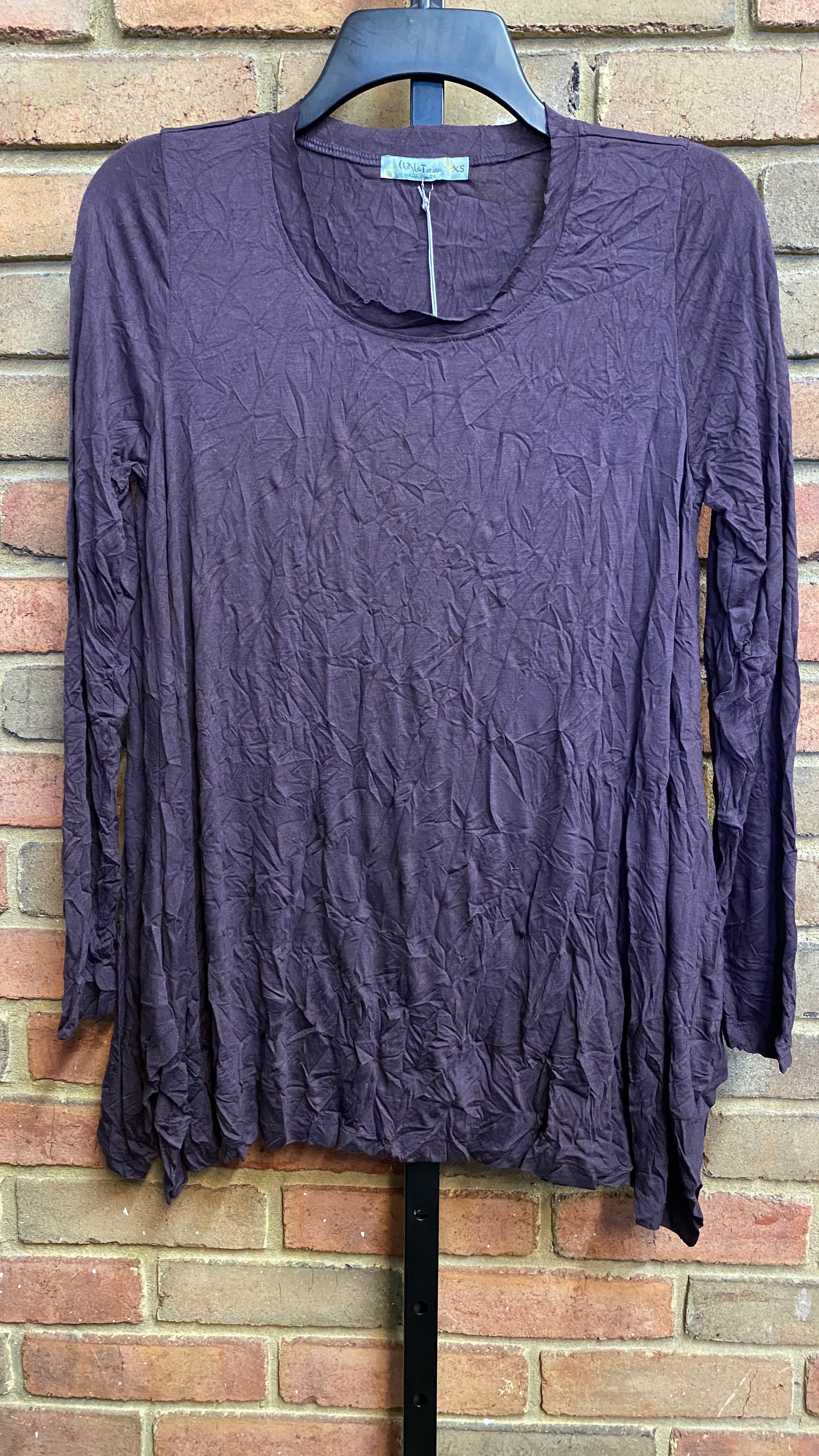 A long-sleeved, round neck Mackenzie Crinkle Top in a maple color displayed on a mannequin against a brick wall background.