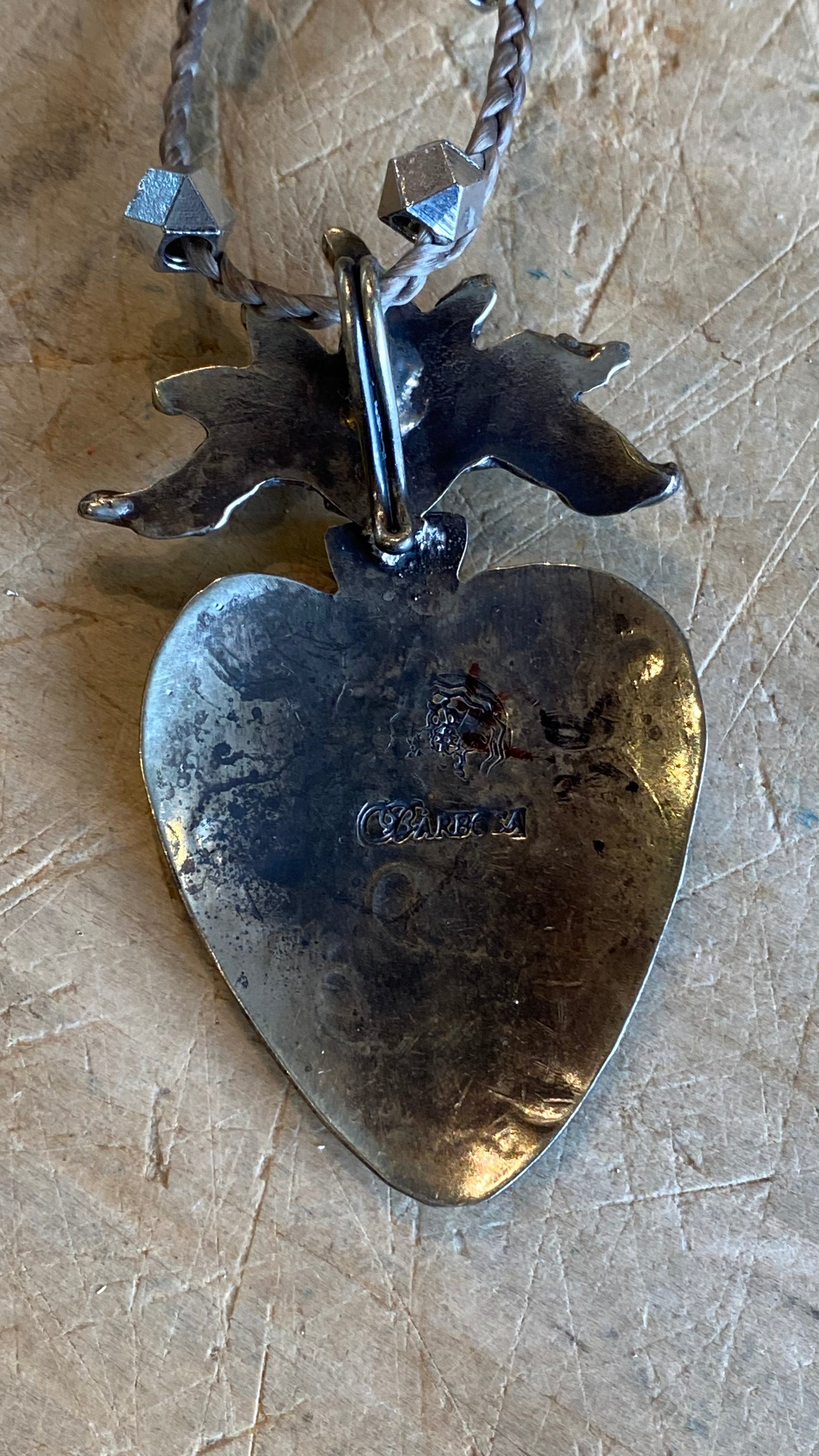Carved Silver Heart with Turquoise Necklace against a light wooden background