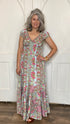 A woman wearing a floral maxi dress with gold foil embellishments, featuring a frill elastic cap sleeve and princess neckline.