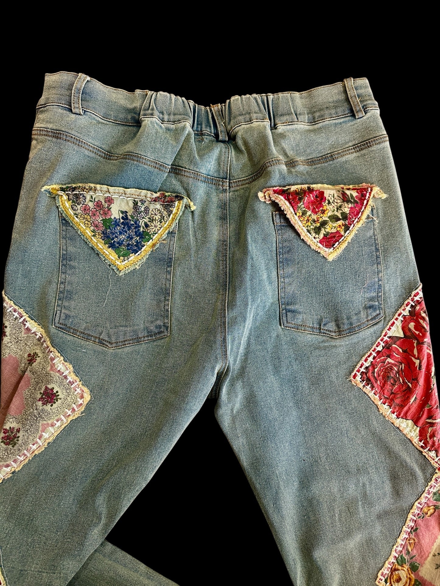 Denim jeans with floral patchwork on a black background