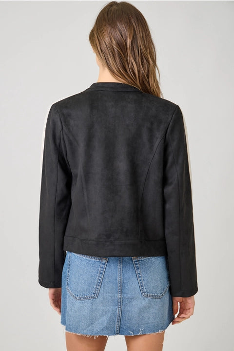 Person wearing a black leather jacket and blue denim skirt on a plain background