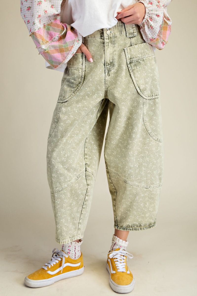 Person wearing light green floral pants with a plain background