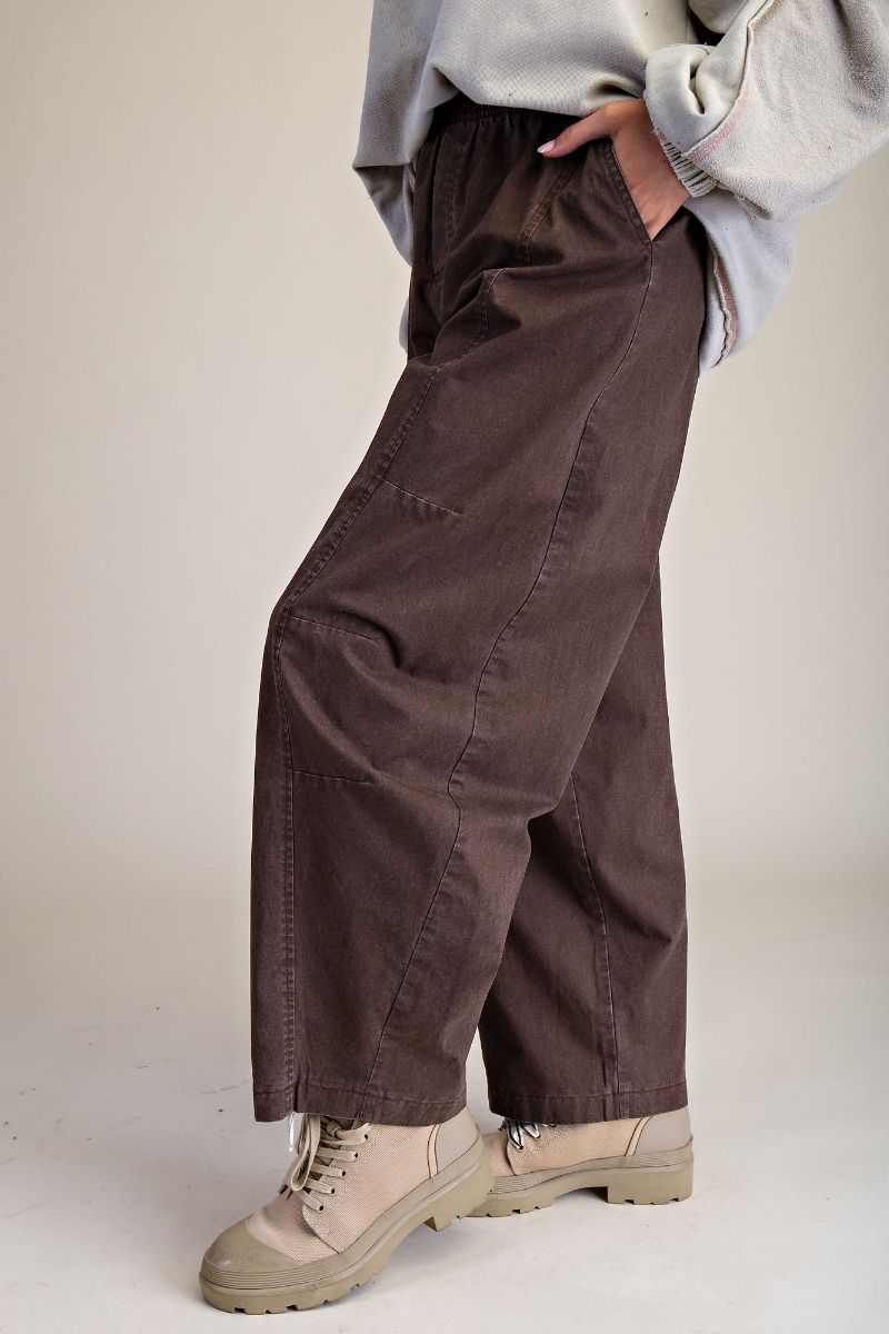 Person wearing brown pull on pants and beige boots on a plain background