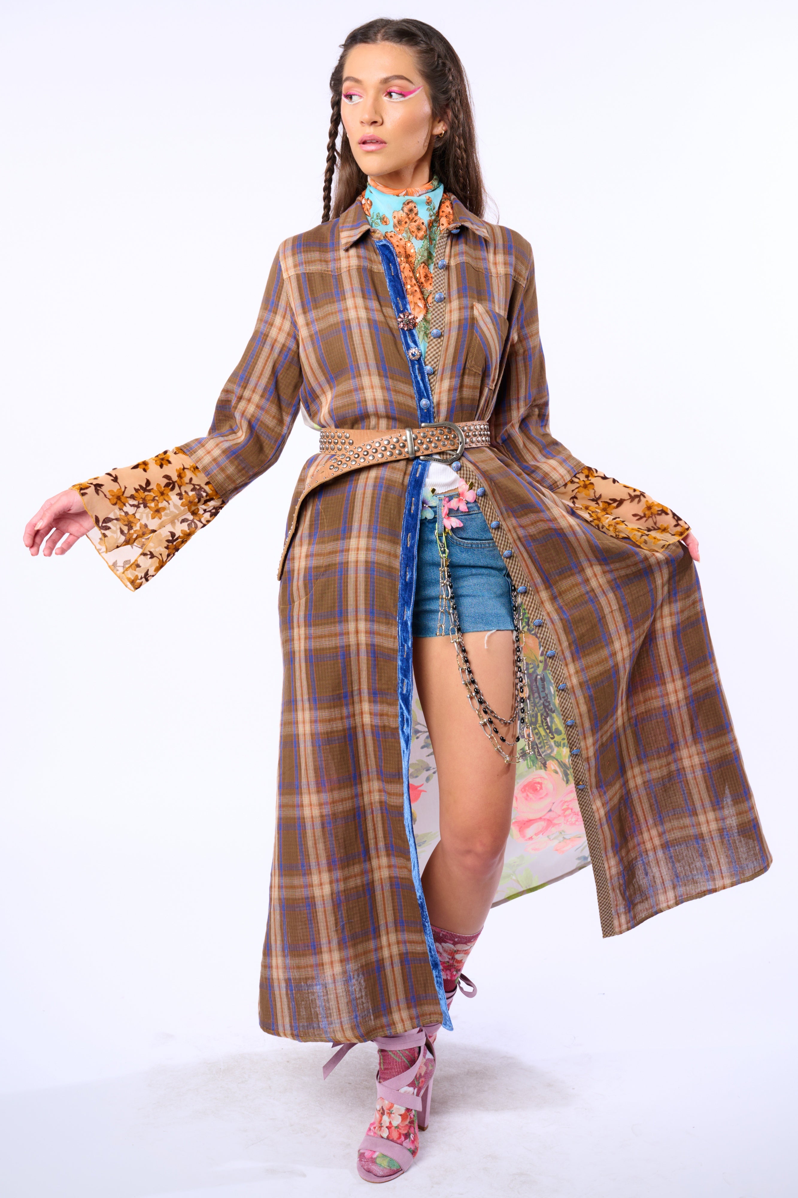 Model wearing a plaid duster with floral patterns and denim shorts on a white background