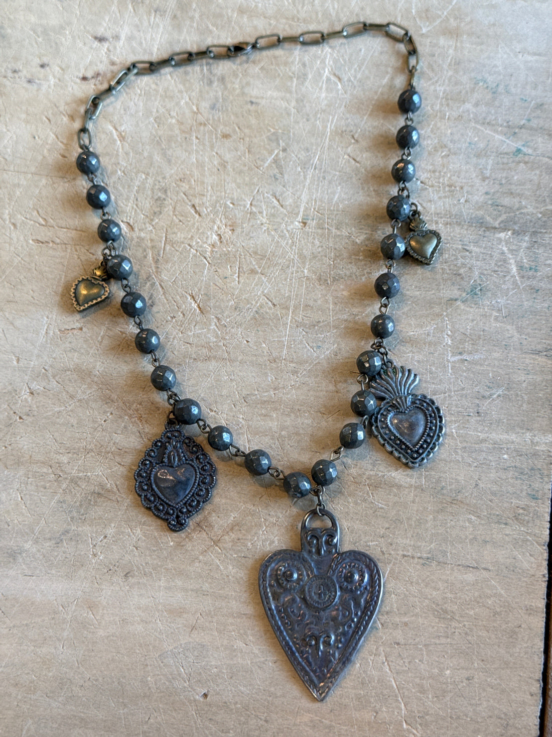 Decorative necklace with heart-shaped pendants on a textured surface
