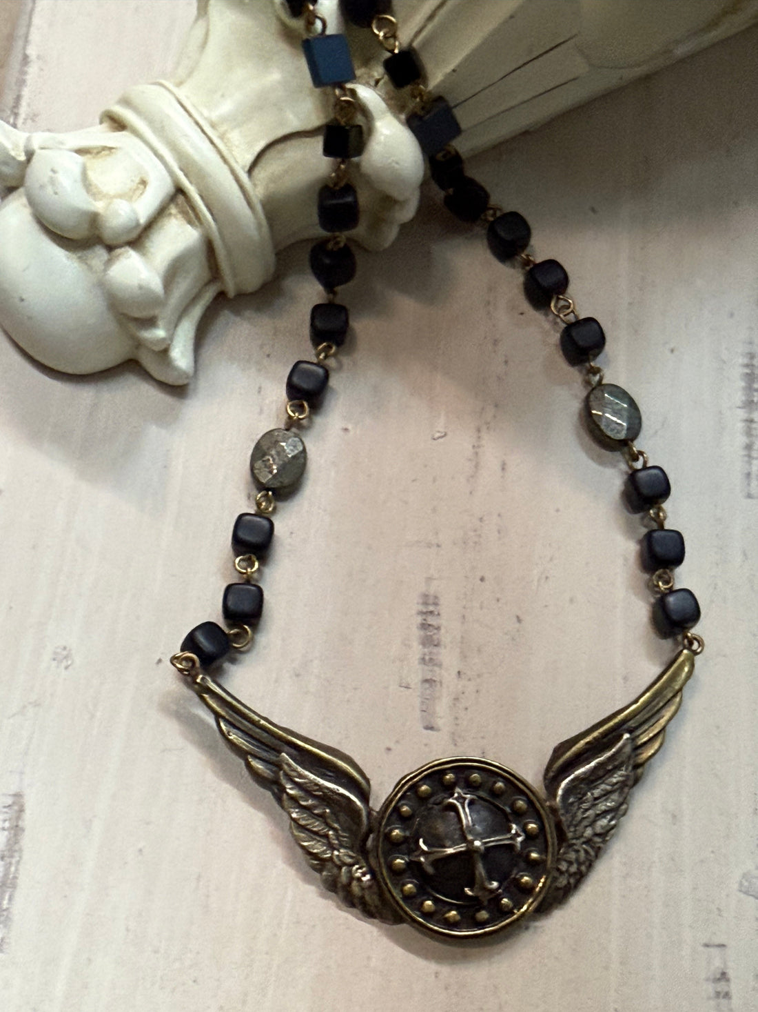 Necklace with black beads and gold accents on a textured surface