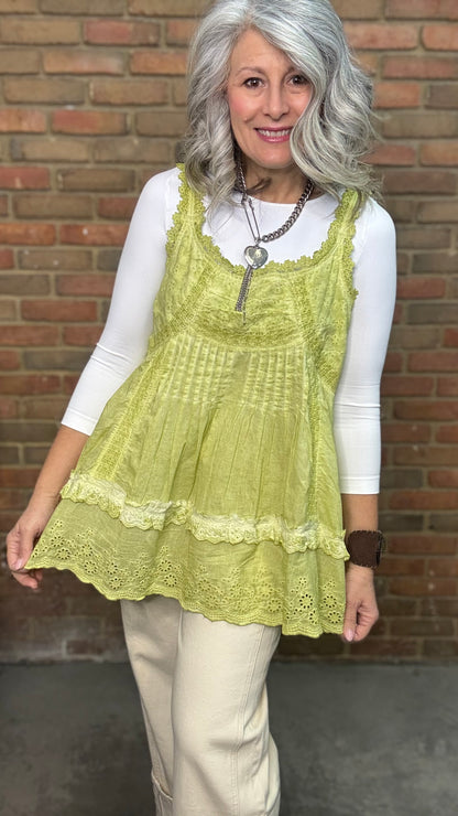 Woman wearing Eyelet Lace Tank over a white shirt, standing against a brick wall.
