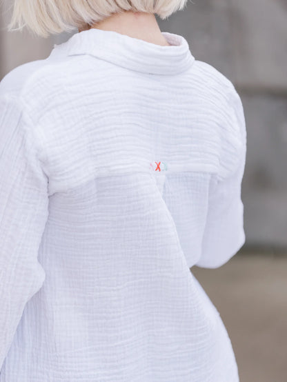 Back view of model wearing Abby Cotton Gauze Button Up Shirt.  Detail of X-Stitching along top yoke of shirt.