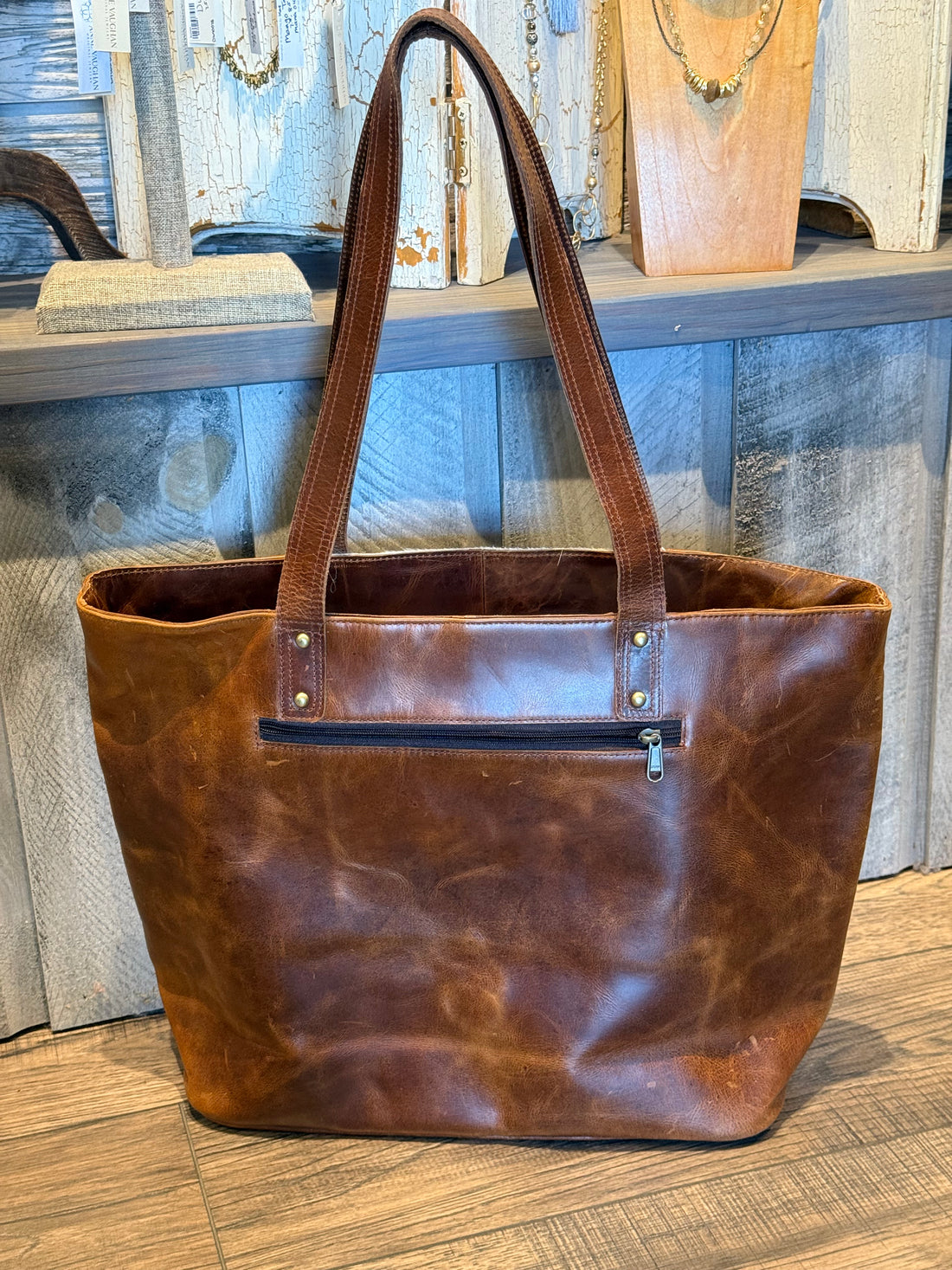 Brown leather tote bag on a wooden surface