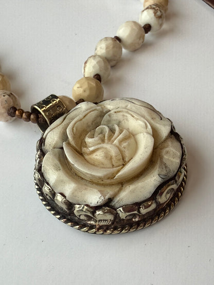Necklace with a detailed rose pendant on a white background