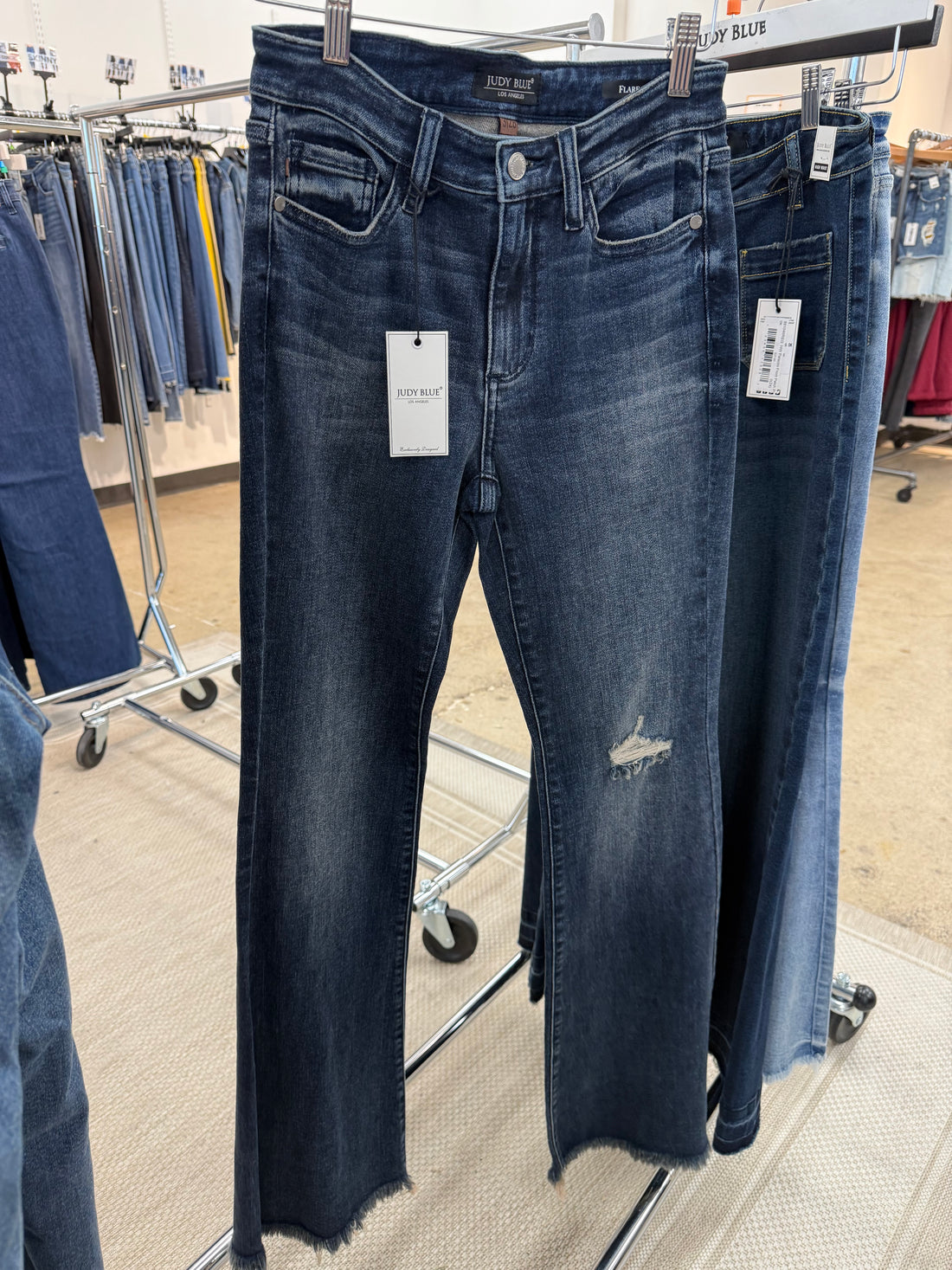 Pair of blue jeans on a clothing rack with tags.