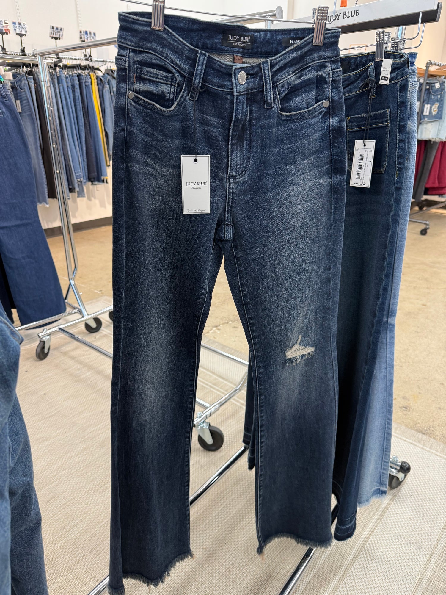 Pair of blue jeans on a clothing rack with tags.