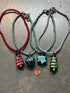 Four beaded necklaces with colorful beads on a gray surface, one next to a penny for scale.