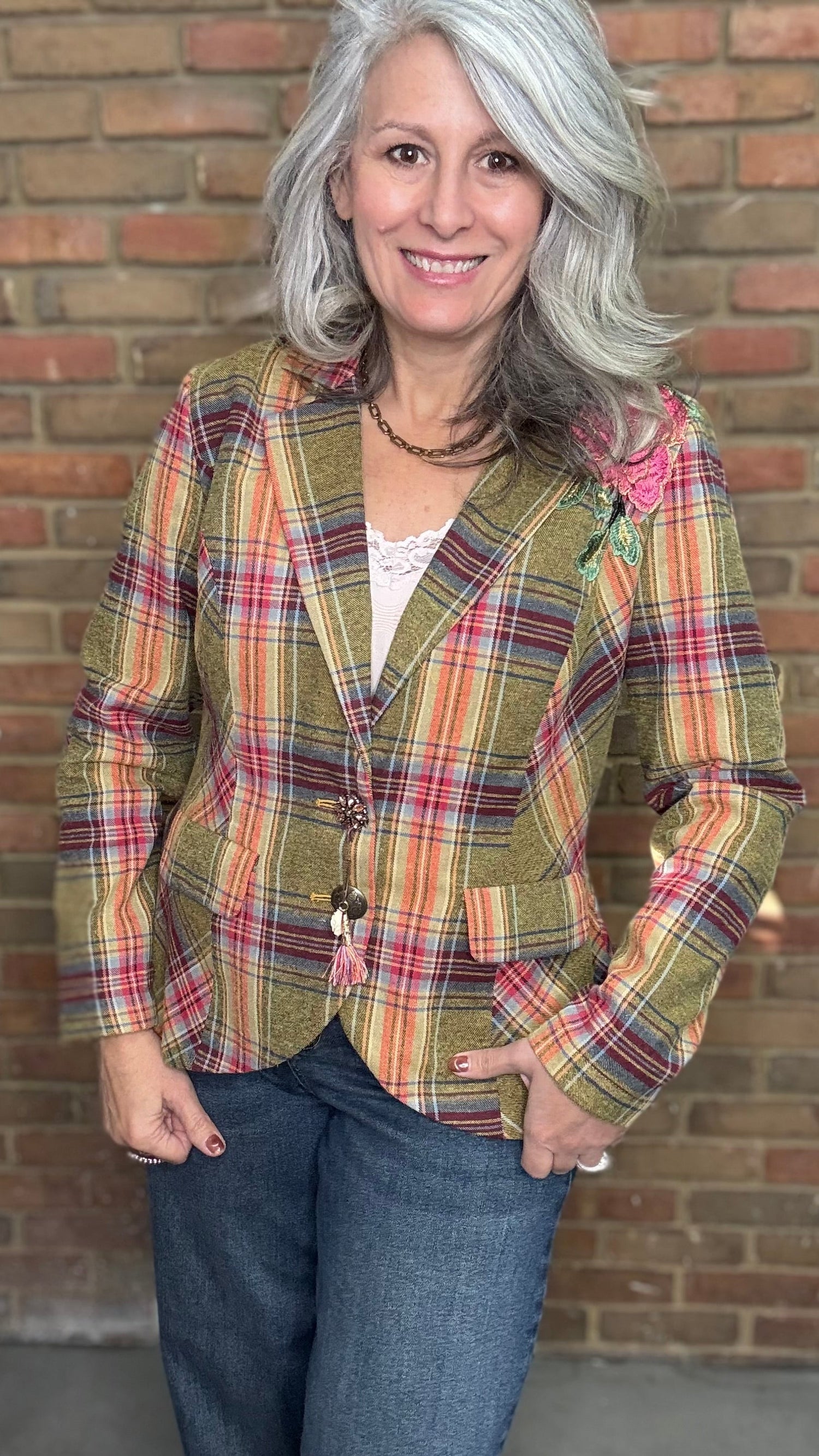 Woman wearing a plaid jacket in front of a brick wall