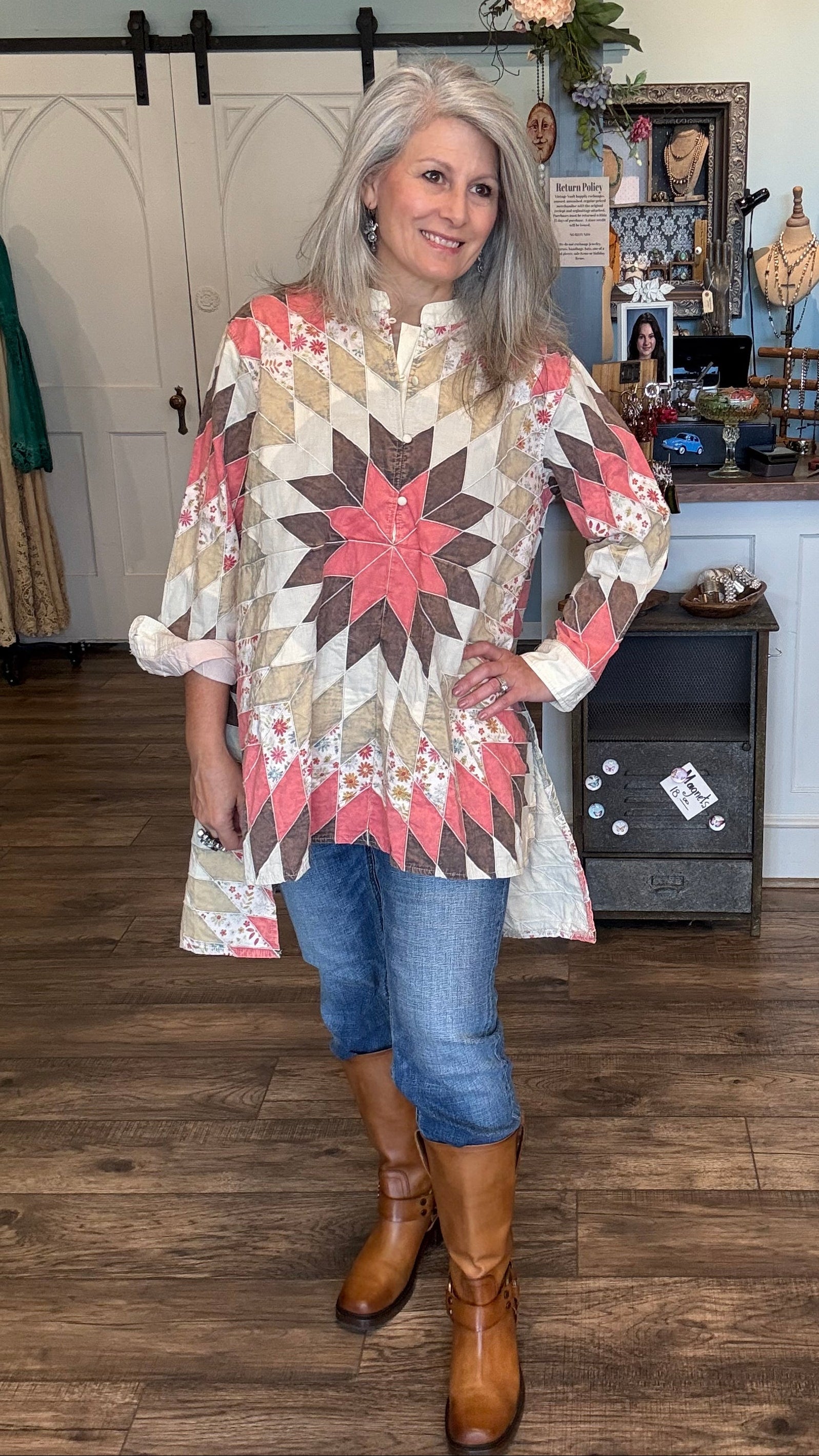 Woman wearing a star-patterned quilted tunic in a room with wooden floors and decorative items.