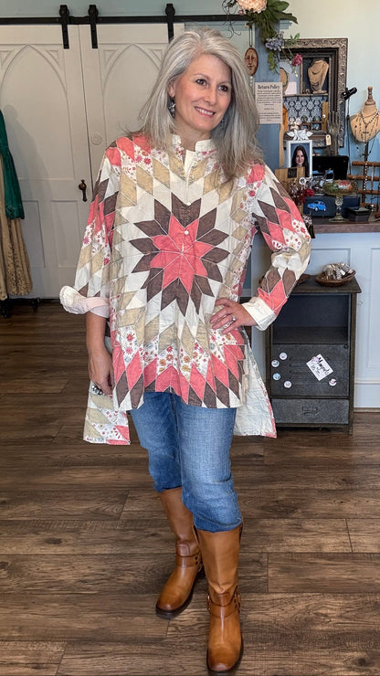 Woman wearing a star-patterned quilted tunic in a room with wooden floors and decorative items.