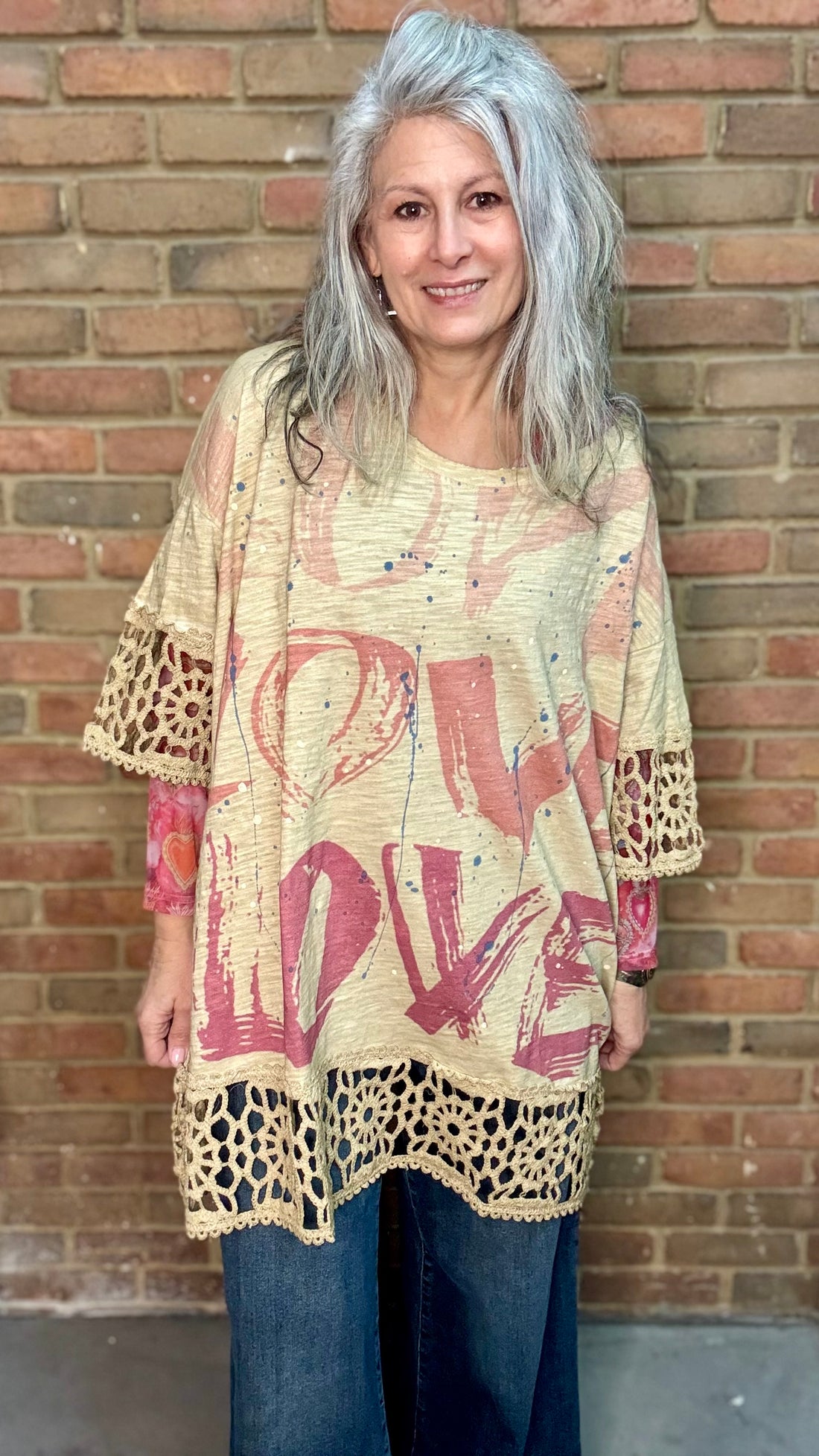 Woman wearing The LOVE top standing against a brick wall.