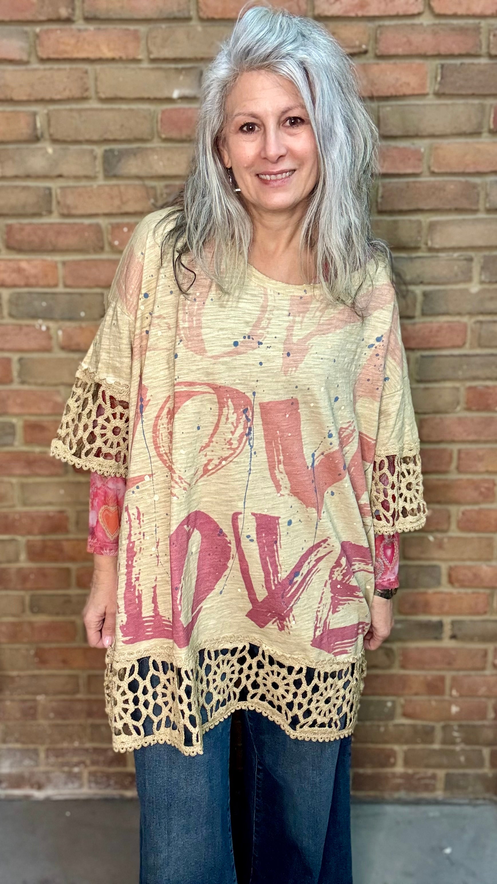 Woman wearing The LOVE top standing against a brick wall.