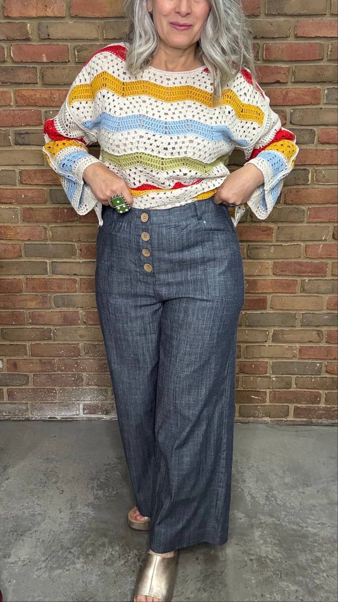 Woman wearing a white t-shirt and Indigo Linen Button Front Pants standing against a brick wall.
