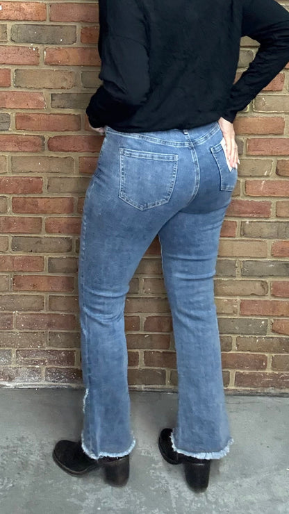 Person wearing The Front Tulip Hem Bootcut Pant jeans standing against a brick wall.