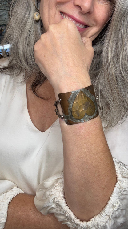 Person wearing a white dress with lace details and a metal half cuff with heart wristband.