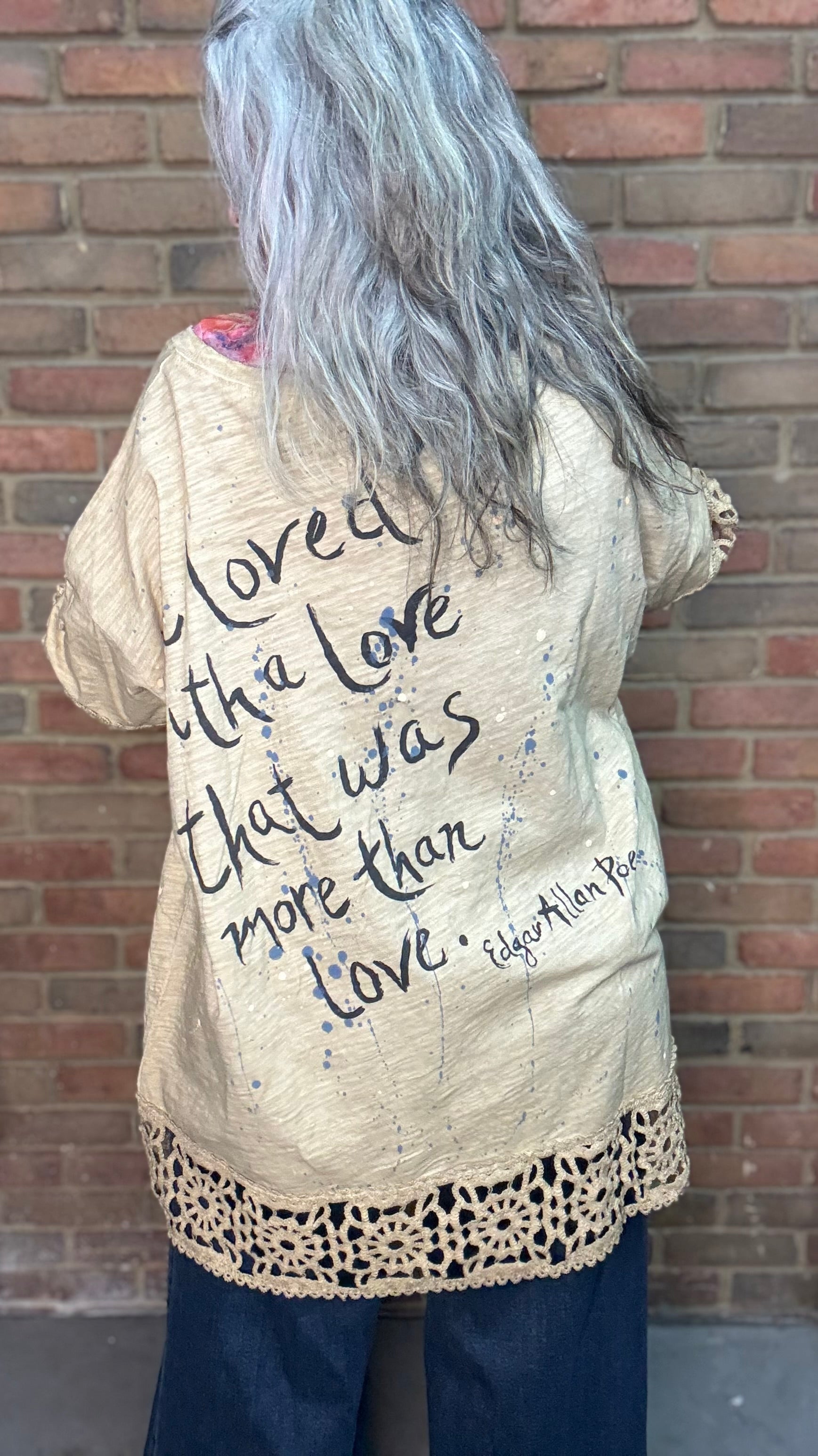 Woman wearing The LOVE top standing against a brick wall.