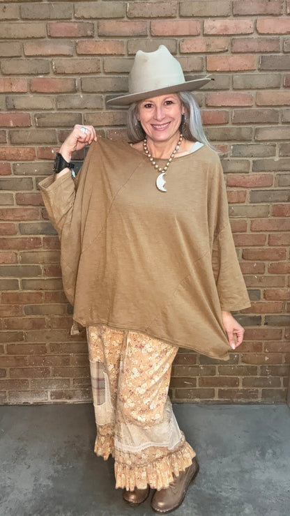 Woman wearing Be Free Top - Vintage Latte and patterned pants against a brick wall.
