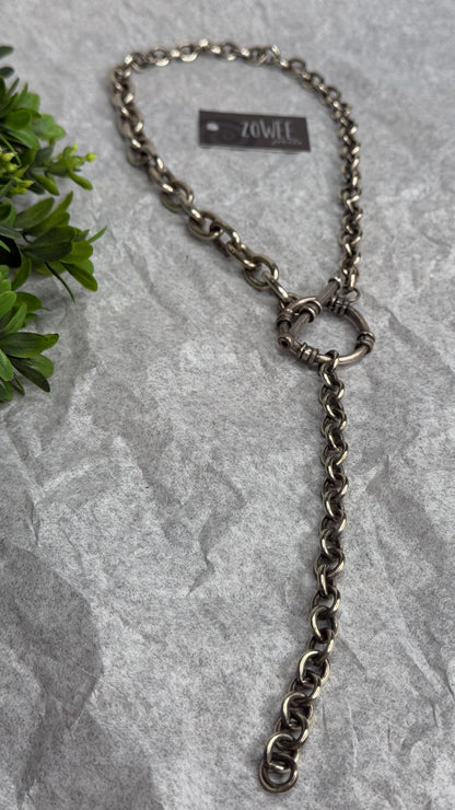Metal chain leash on a textured stone surface with a plant in the corner
