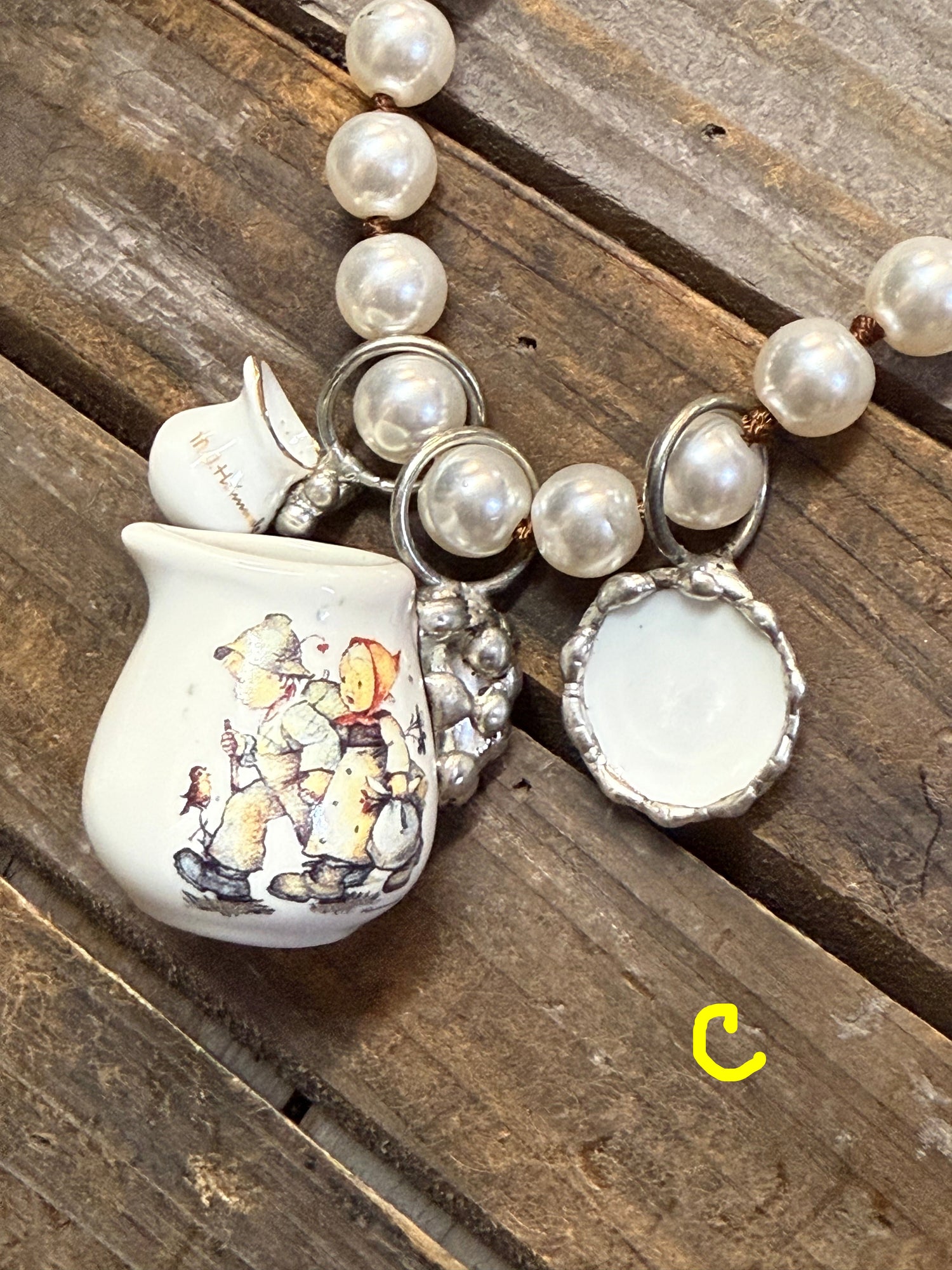 Necklace with teapot charm featuring illustrations on a wooden surface