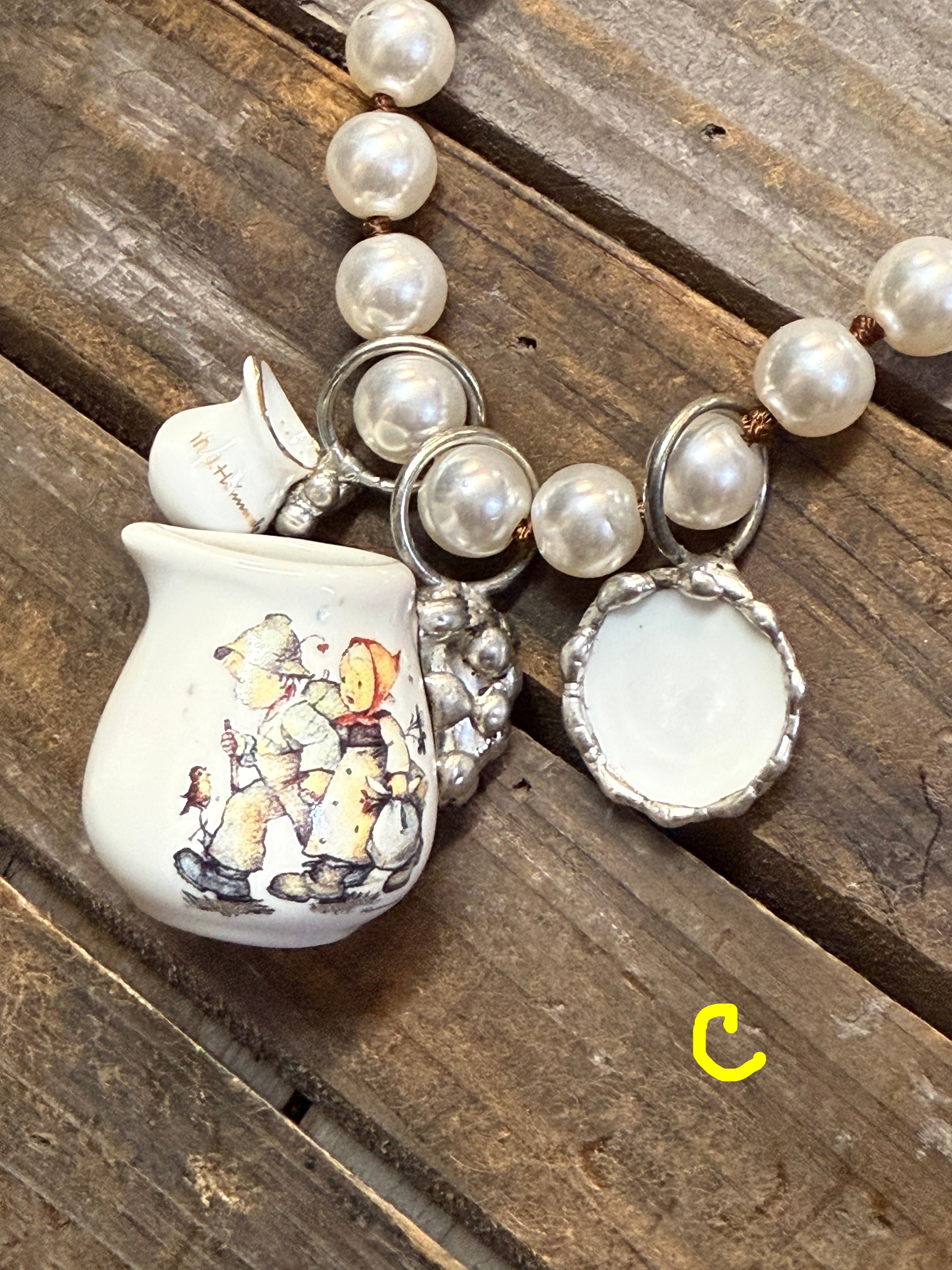 Necklace with teapot charm featuring illustrations on a wooden surface