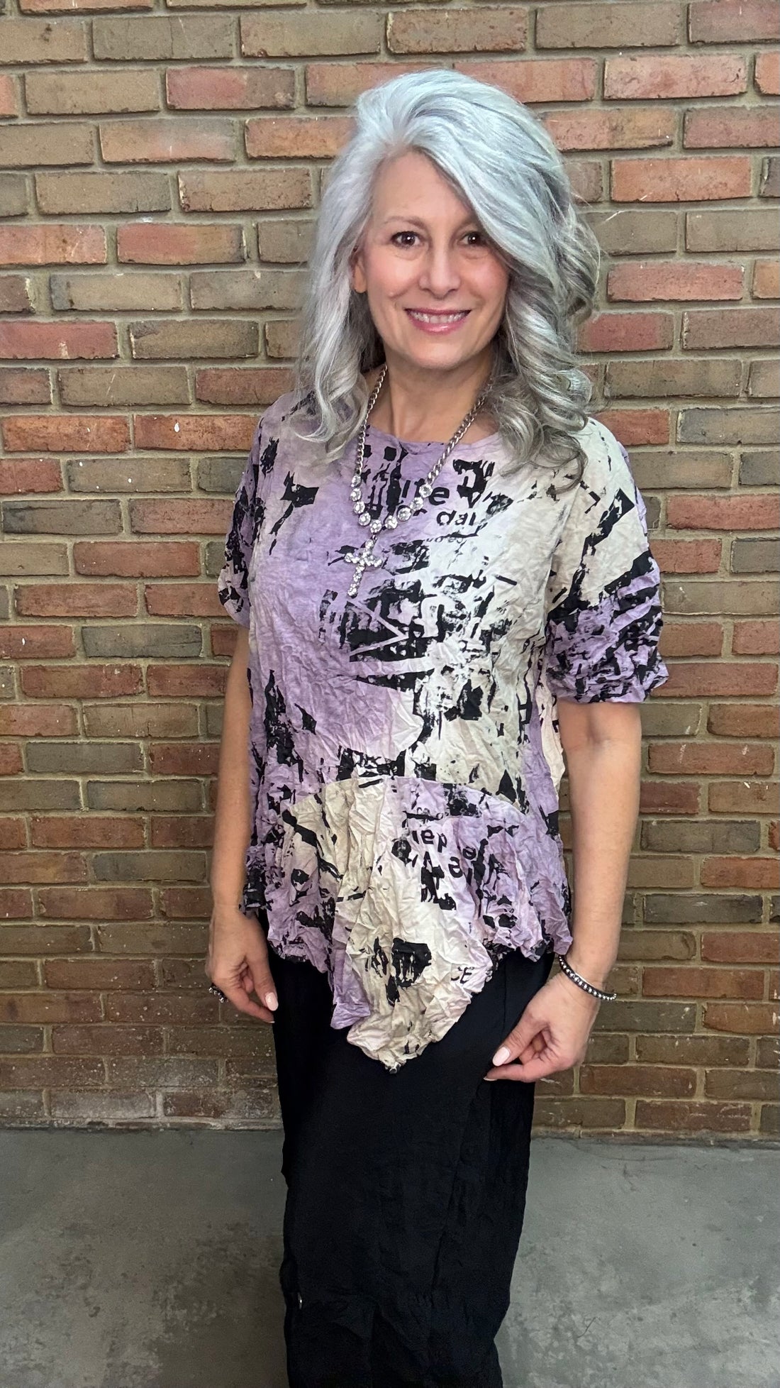 Woman wearing Matilda Top - Aura with a brick wall background