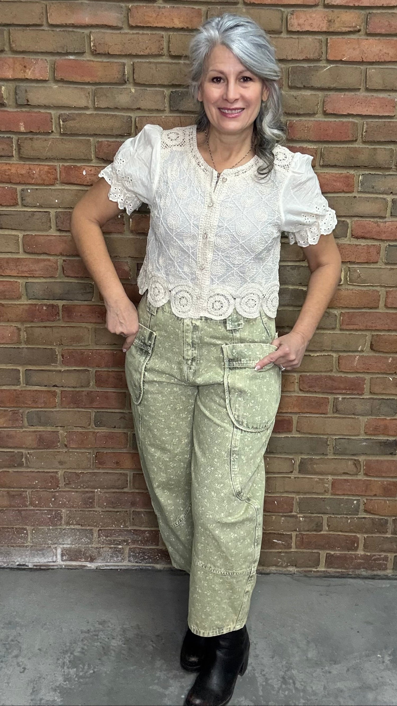 Woman wearing the Crochet Embroidery Button-Up Top and Floral Printed Barrel Pants with a brick wall background