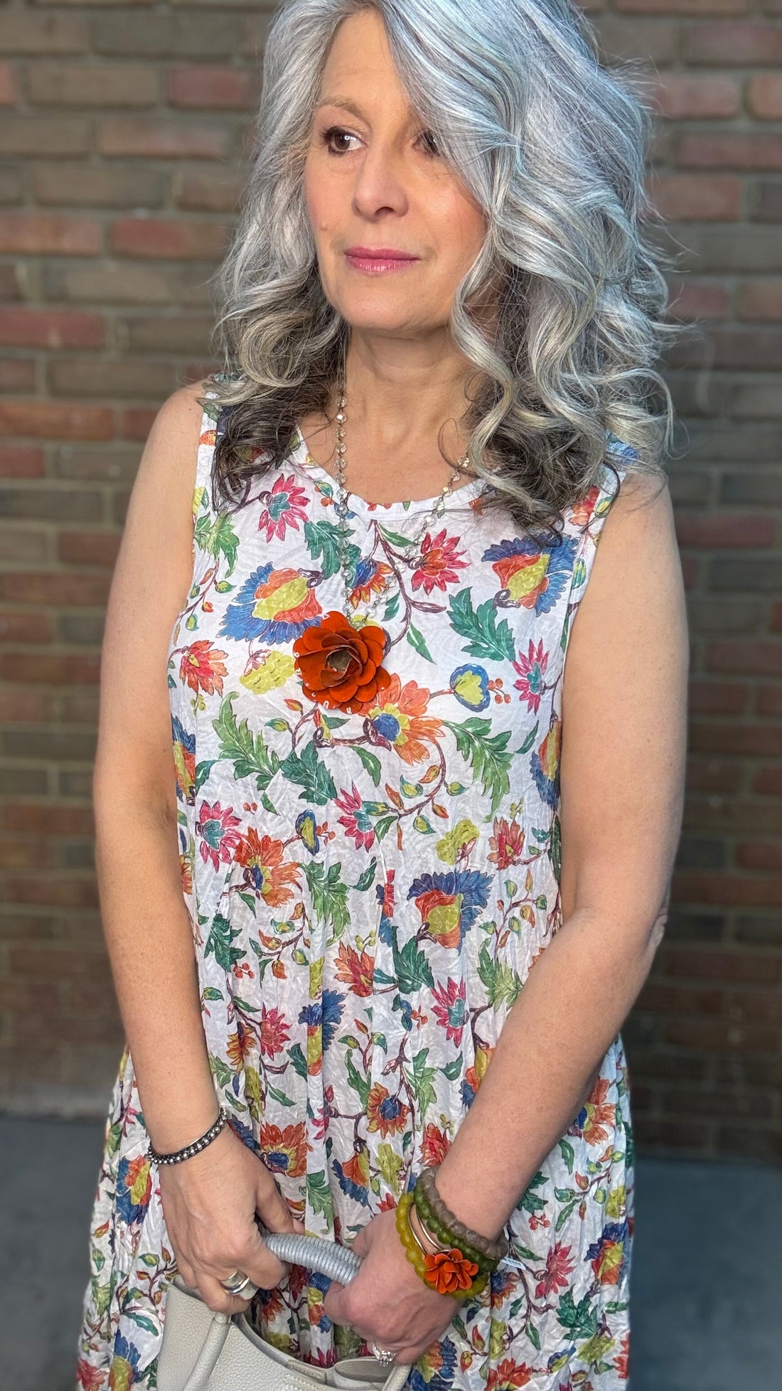 Woman in Bright Floral Crinkle Tank Dress standing against a brick wall