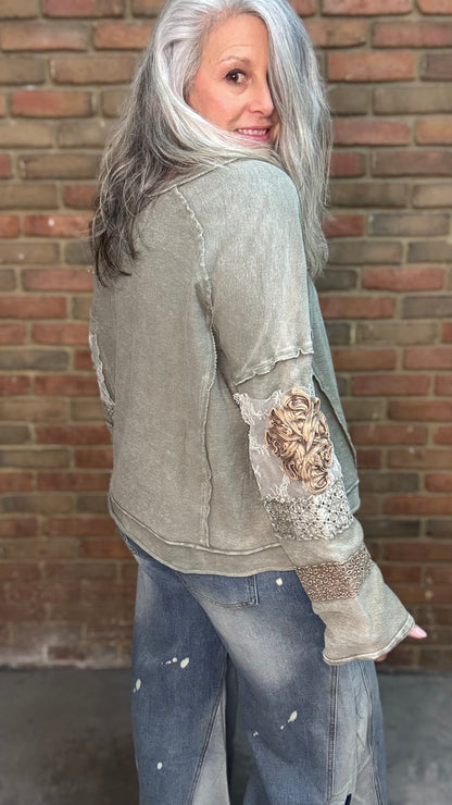 Woman wearing the Olive Embellished Sleeve Top and Bleached Wide Leg Jeans standing against a brick wall.