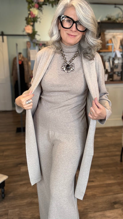 Woman in a khaki outfit with a long coat in an indoor setting