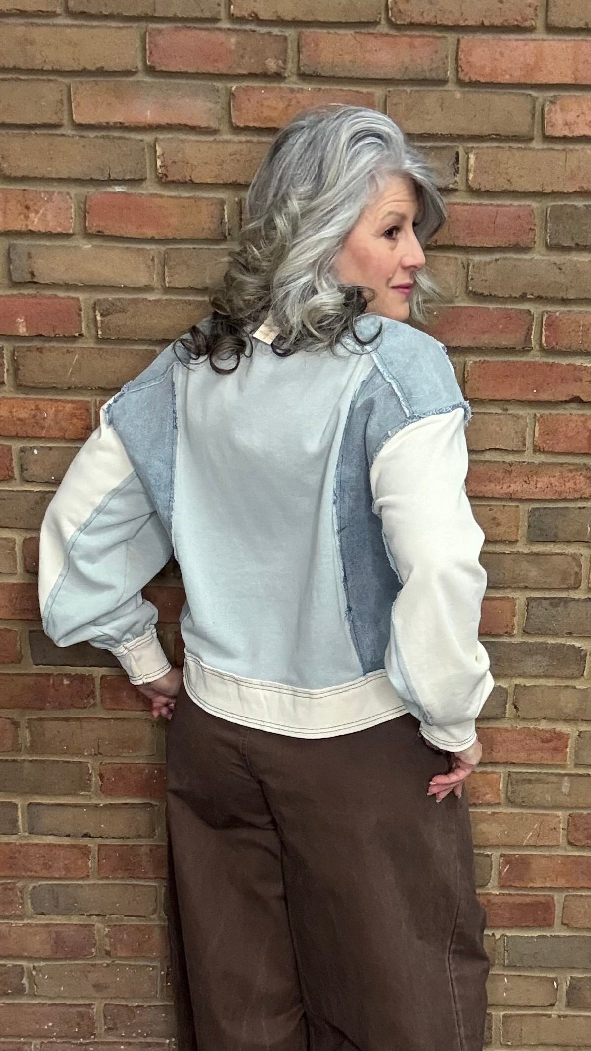 Person wearing the Color Block Pullover Top and the brown pullon barrel pants standing against a brick wall.