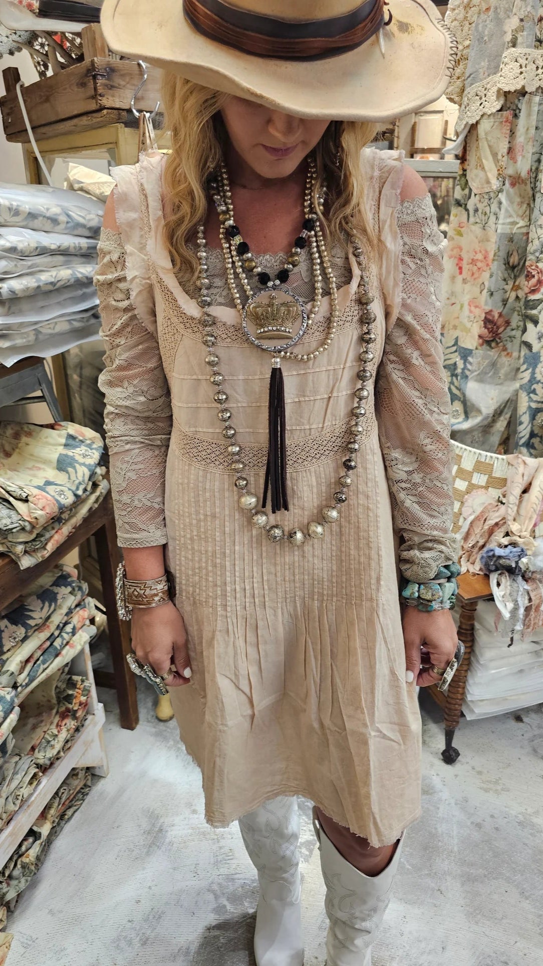 Woman in a beige dress and hat standing in a store