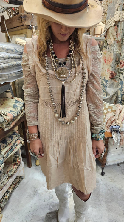 Woman in a beige dress and hat standing in a store